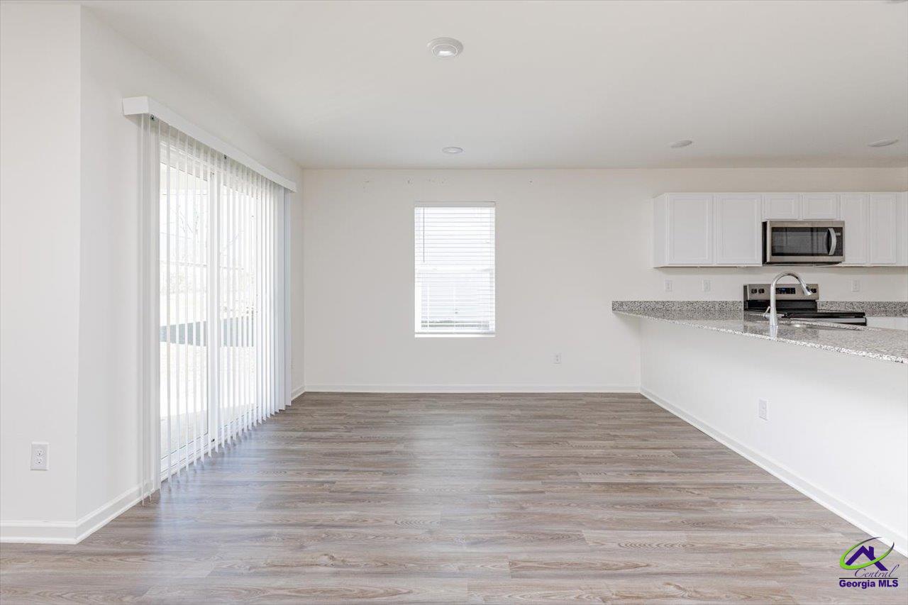 Open dining area with gray wood-look floors, a kitchen counter, and sliding glass door.