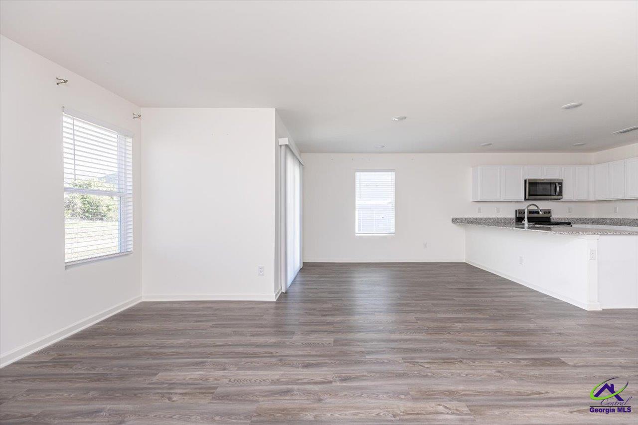 Open-plan living and kitchen area with gray wood-look flooring, white cabinetry, and a peninsula.