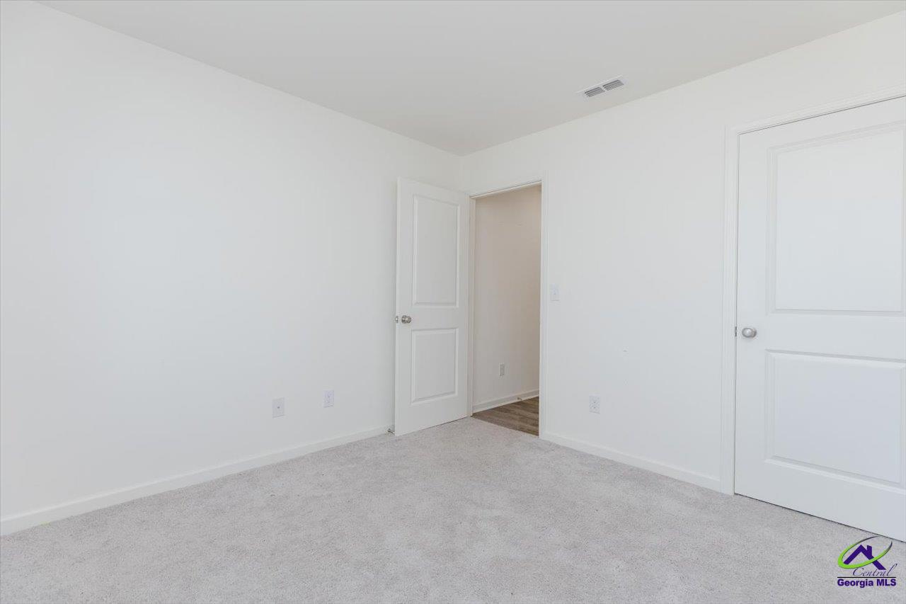 Vacant bedroom with light gray carpet, white walls, and two paneled doors.