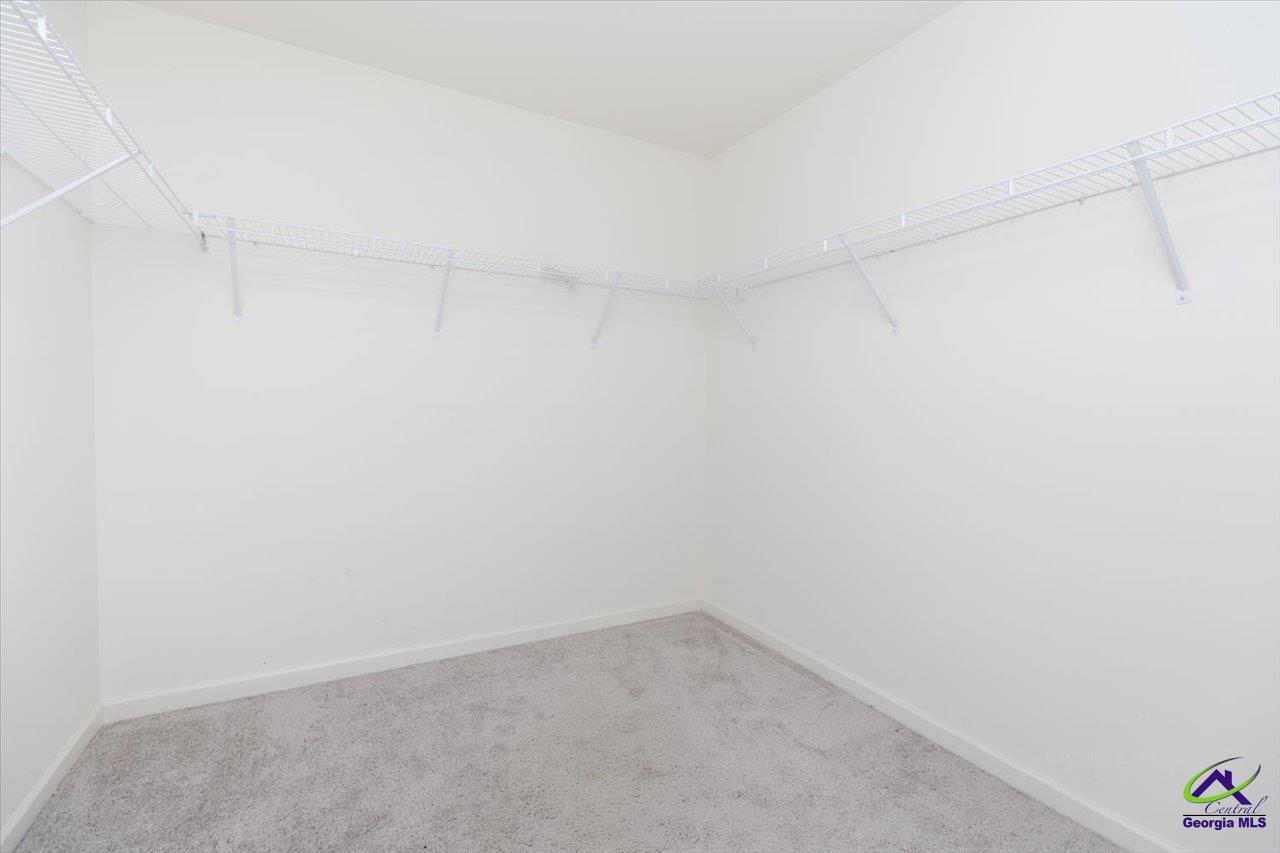Empty walk-in closet with gray carpet and white wire shelving along three walls.