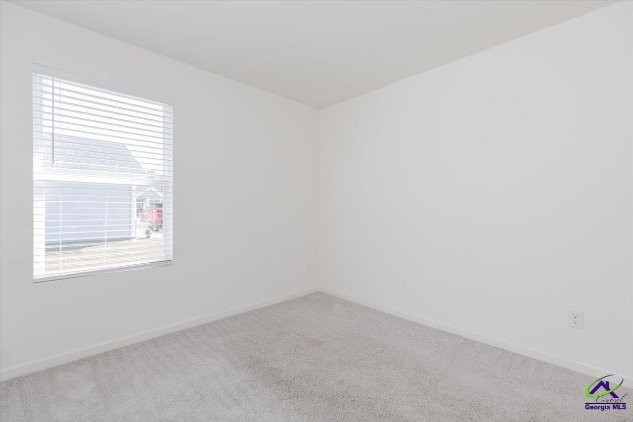 Empty room with light gray carpet and a window with white blinds.