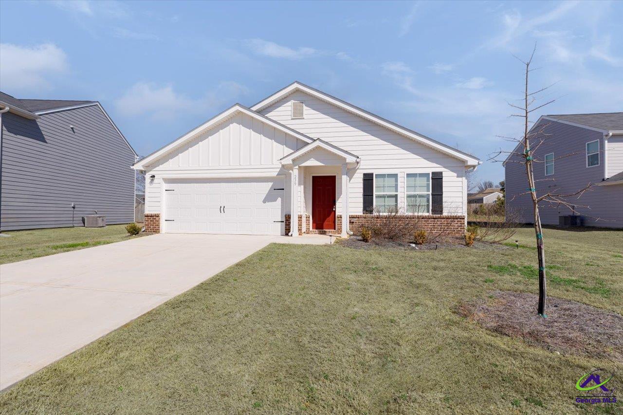 White single-story home with a red front door, brick facade, and attached two-car garage.