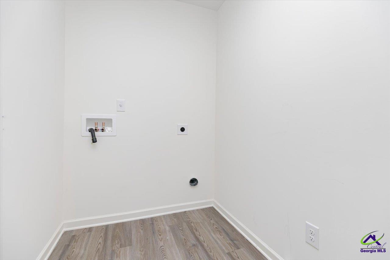 Empty laundry area with washer and dryer hookups and gray wood-look flooring.