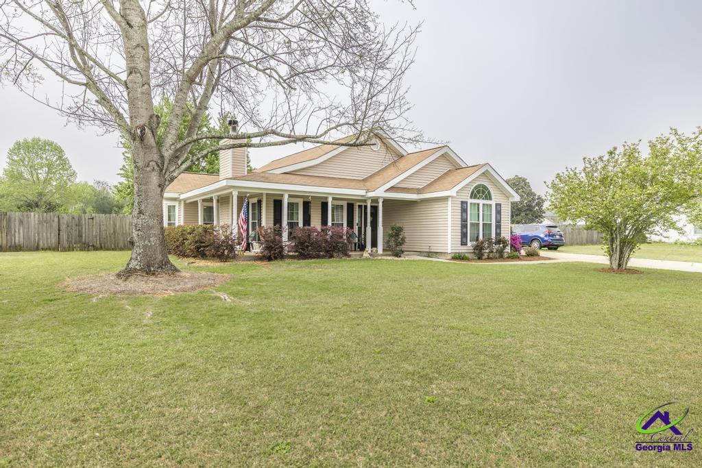 Single-story beige home with a covered porch, arched window, and broad front lawn.
