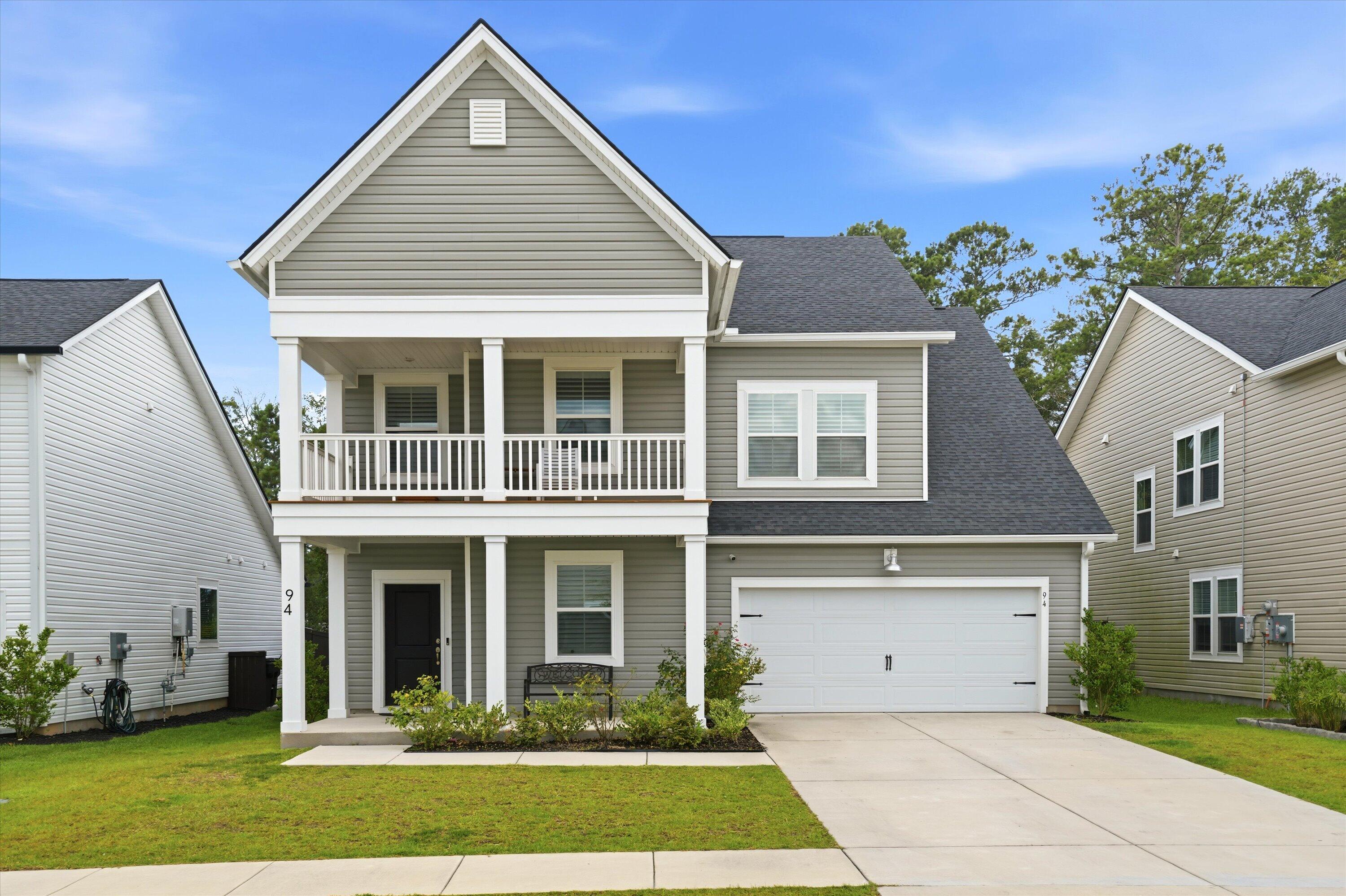 Two-story gray house with white trim, an upper balcony, and an attached two-car garage.