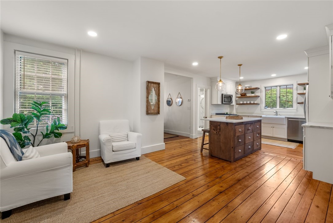 Open-plan living room and kitchen with a dark wood island and wide-plank hardwood floors.