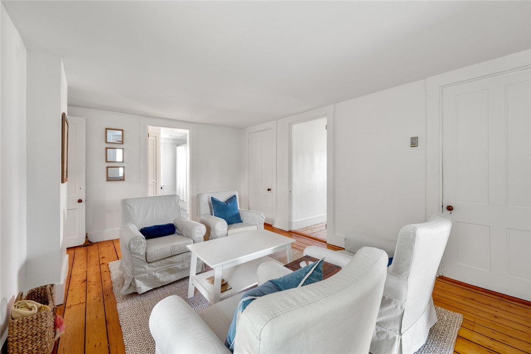 Living room with white slipcovered seating, a patterned rug, and warm wood floors.