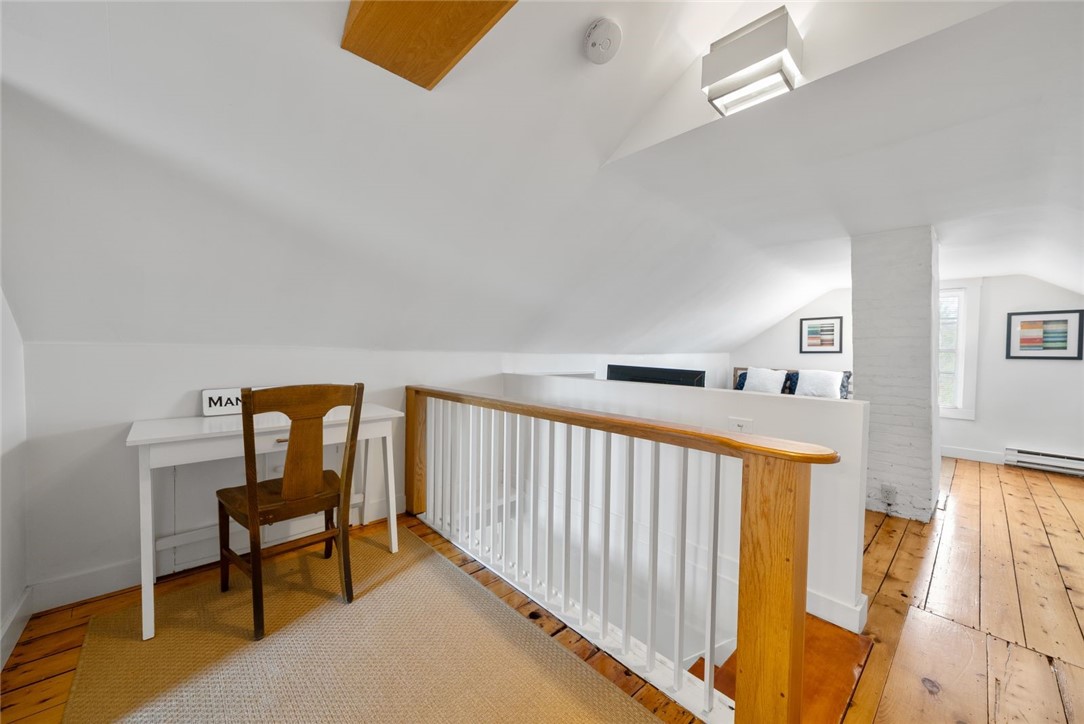 Loft landing with a small desk, wooden chair, and wood-and-white stair railing.
