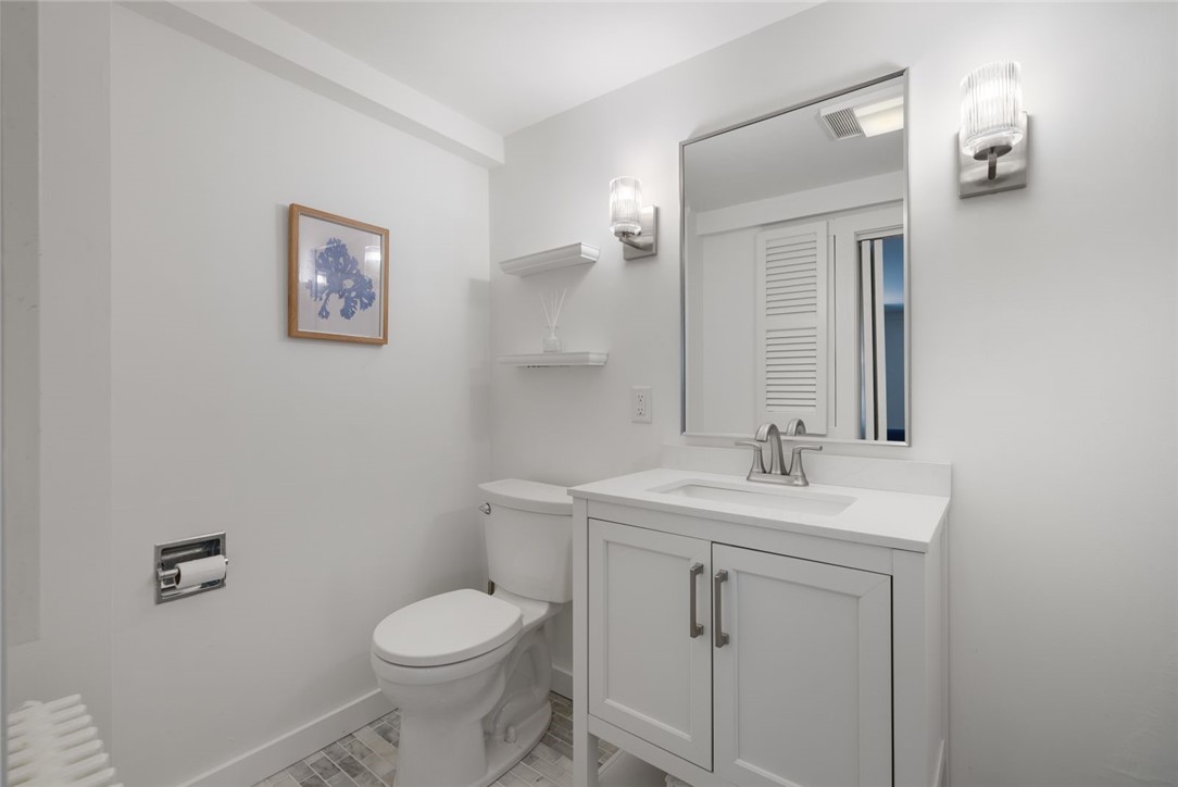 Bathroom with a white vanity, large mirror, toilet, and gray patterned tile floor.