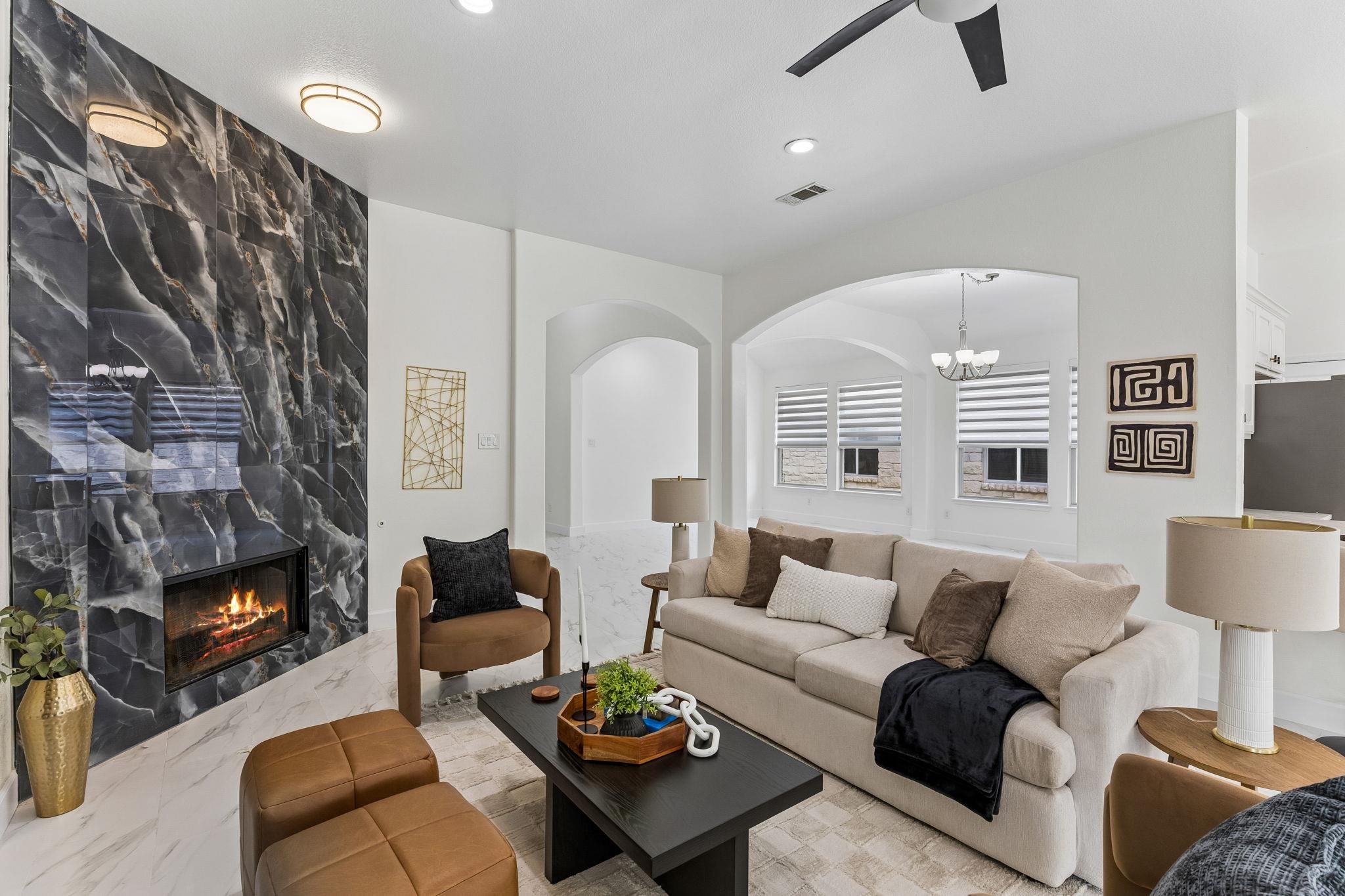 Staged living room with a dramatic dark marble fireplace wall and neutral seating.