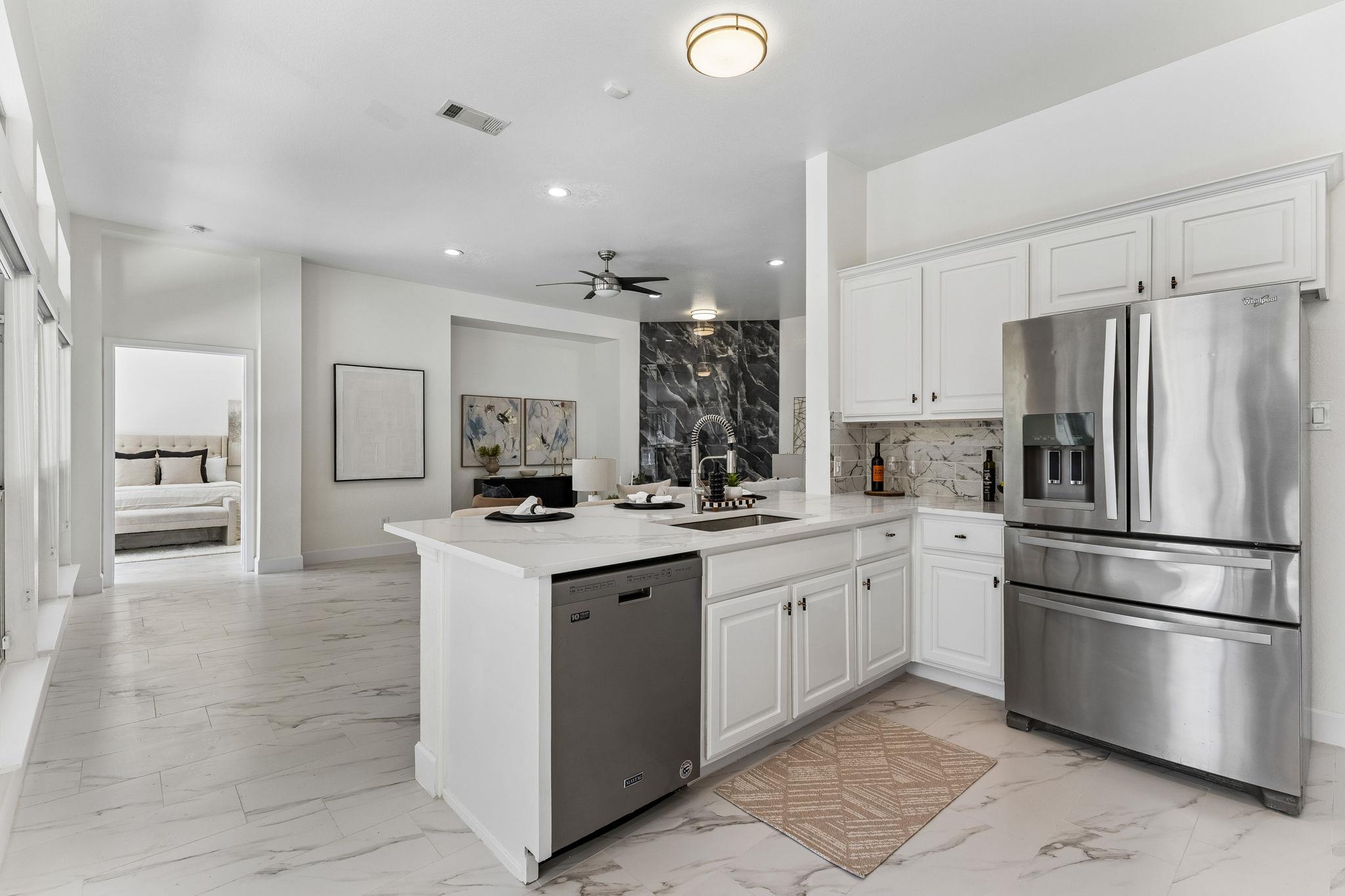 Bright kitchen with a large marble island, white cabinetry, stainless appliances, and a black marble accent wall.