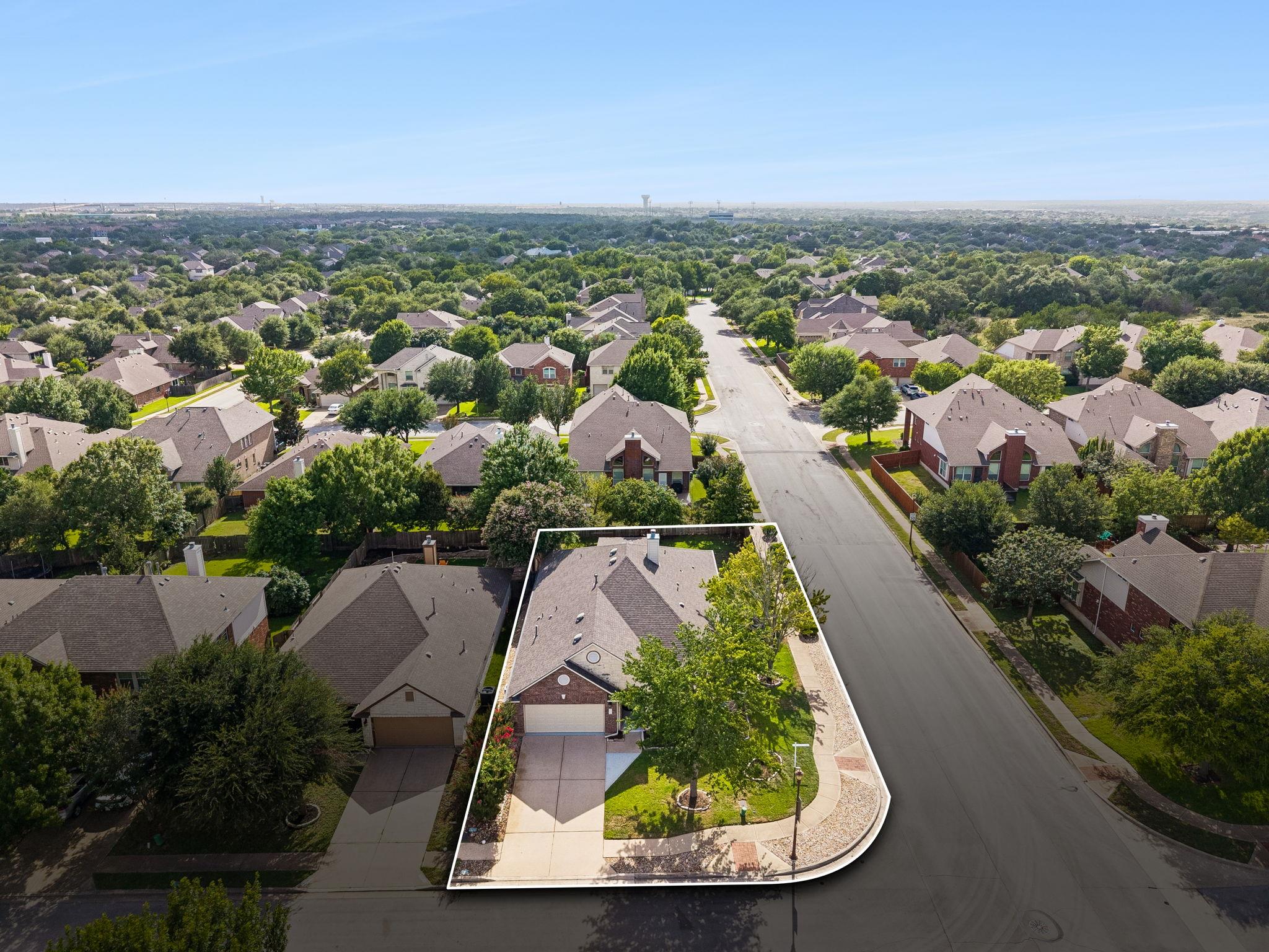 Aerial view of the home and outlined corner lot in a tree-lined neighborhood.
