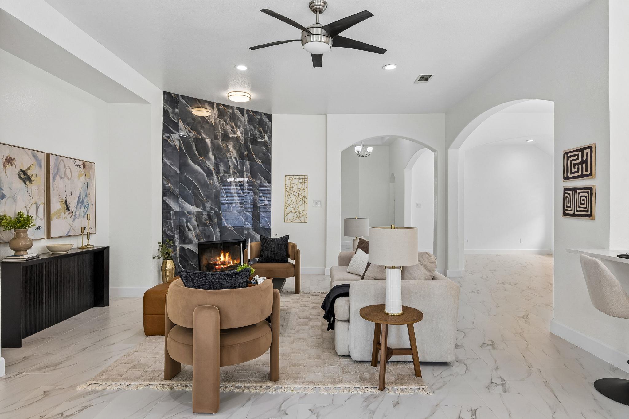 Staged living room with a marble fireplace wall, arched openings, and contemporary seating.