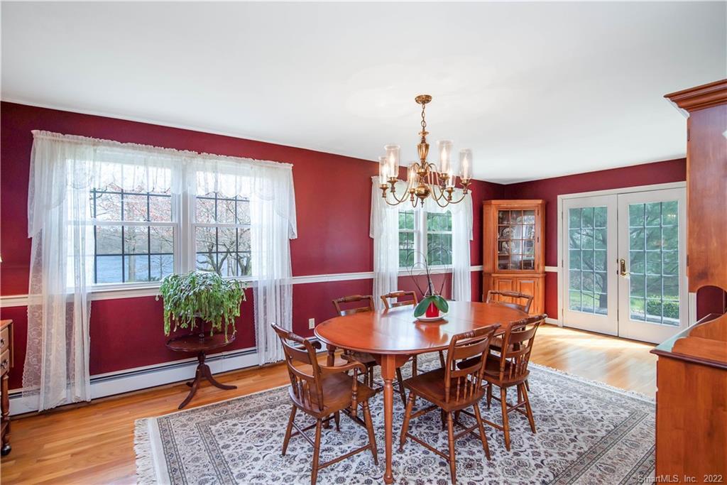 Dining room with burgundy walls, a wooden table, hardwood floors, and French doors overlooking the garden.