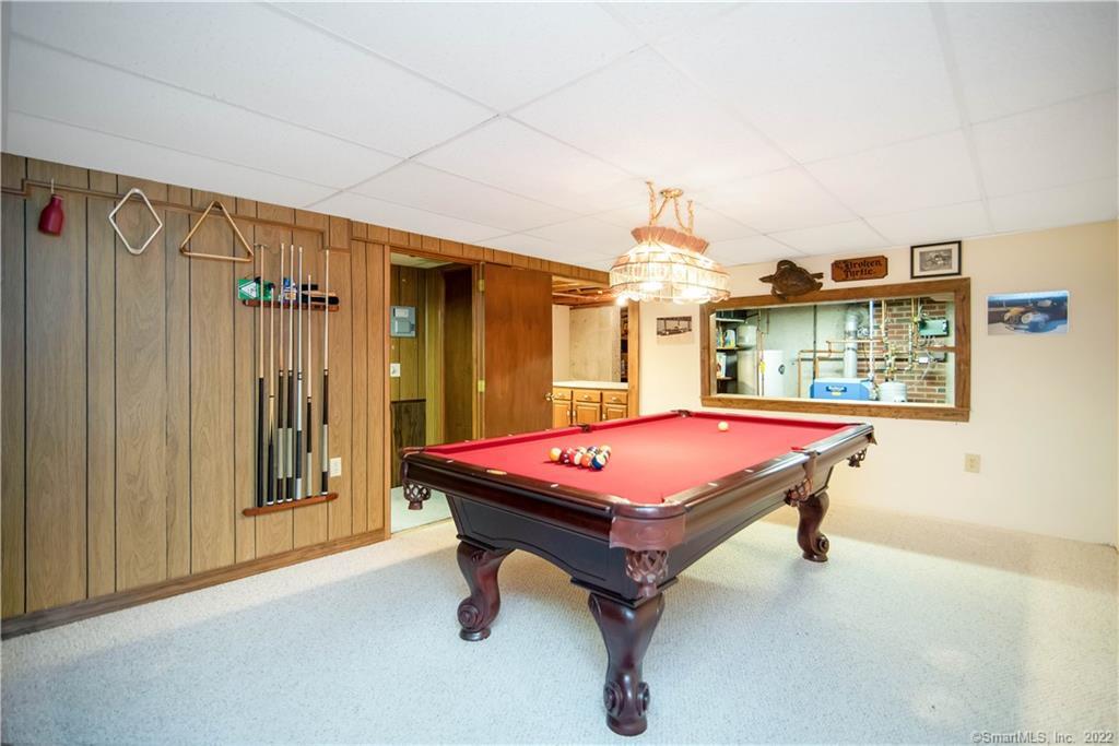 Game room with a red-felt pool table, wall-mounted pool cues, and wood-paneled walls.