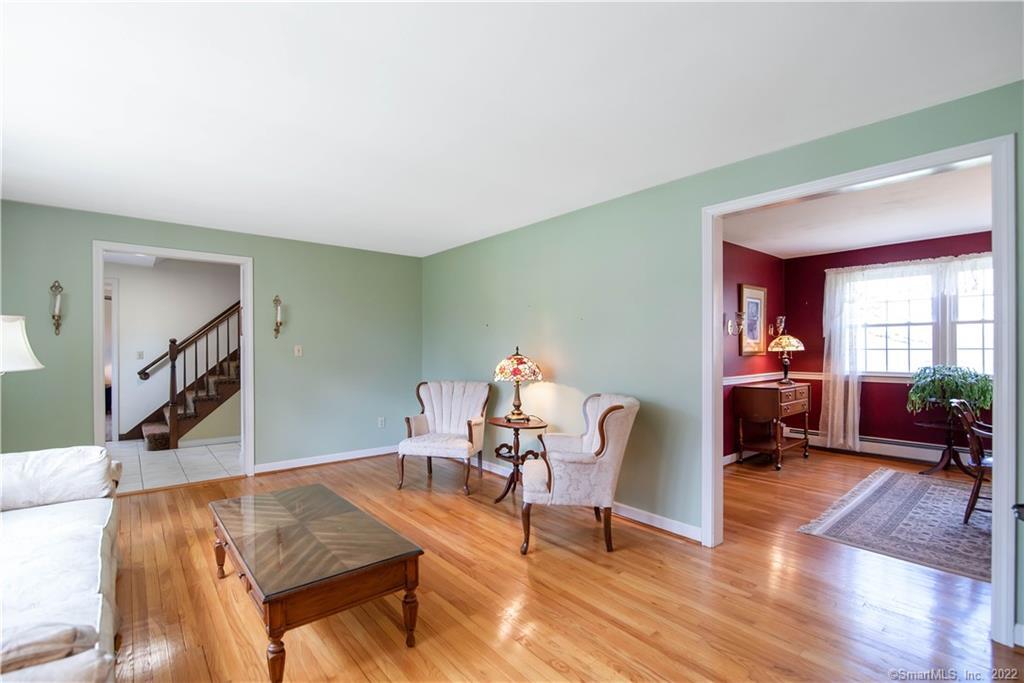 Living room with hardwood floors, pale green walls, and an adjoining burgundy room.