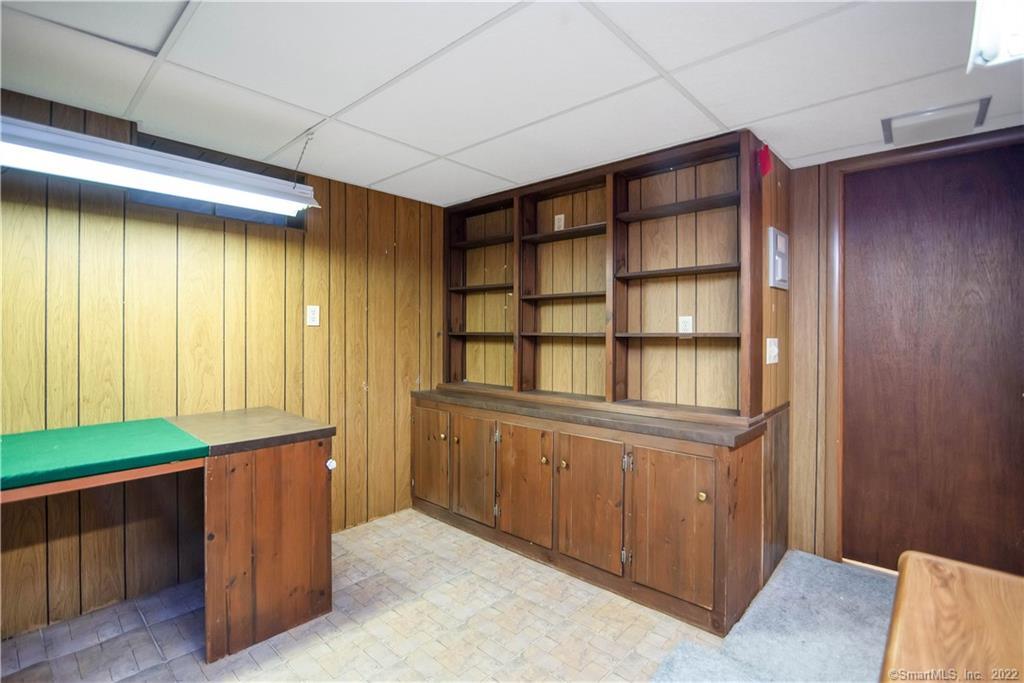 Wood-paneled room with built-in shelving and cabinets and a green-topped counter.