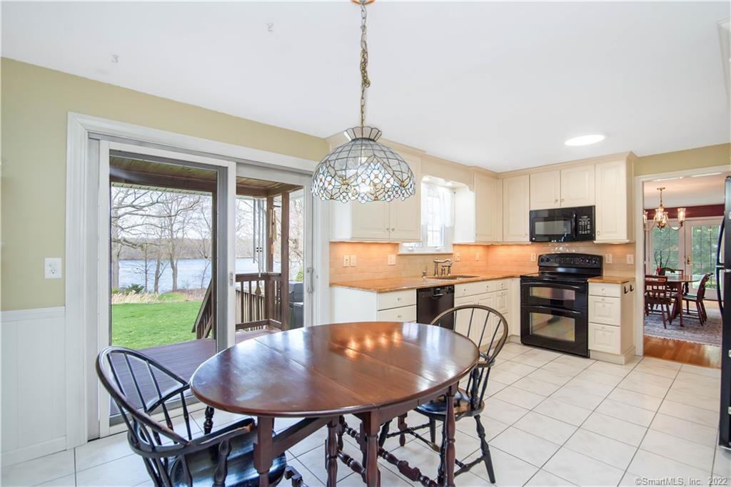 Kitchen and dining area with cream cabinetry, a wooden table, and sliding doors overlooking the water.