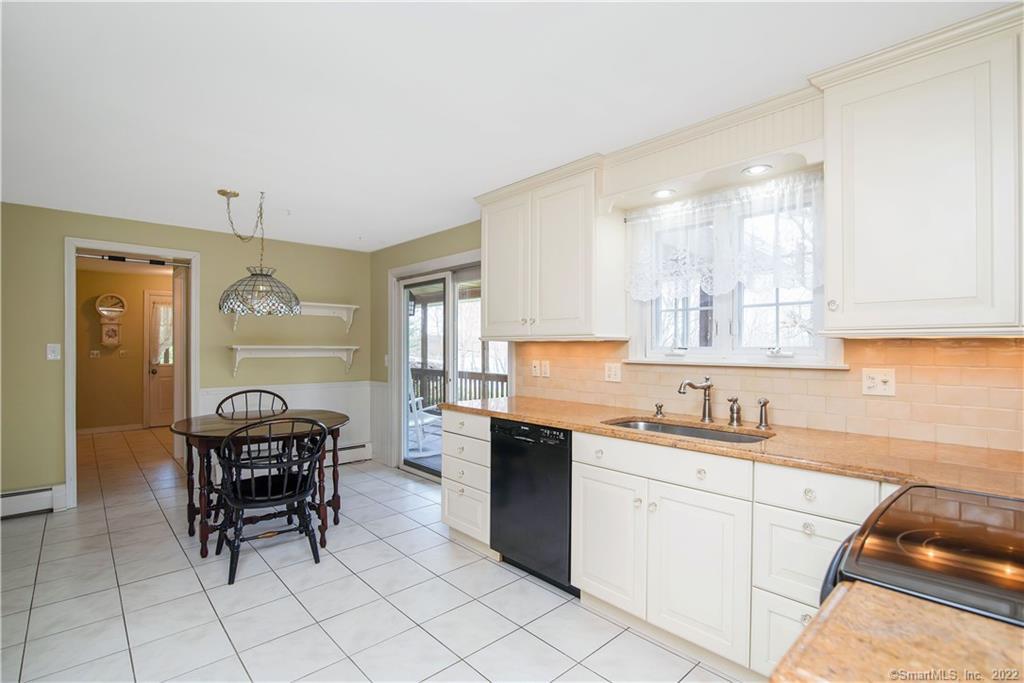 Kitchen with white cabinetry, tan countertops, and a round dining table beside a sliding glass door.