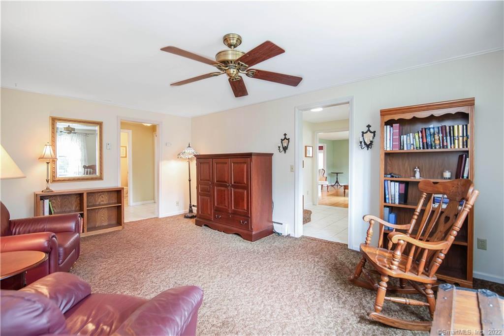 Furnished living room with burgundy leather seating, a bookcase, and a wooden rocking chair.
