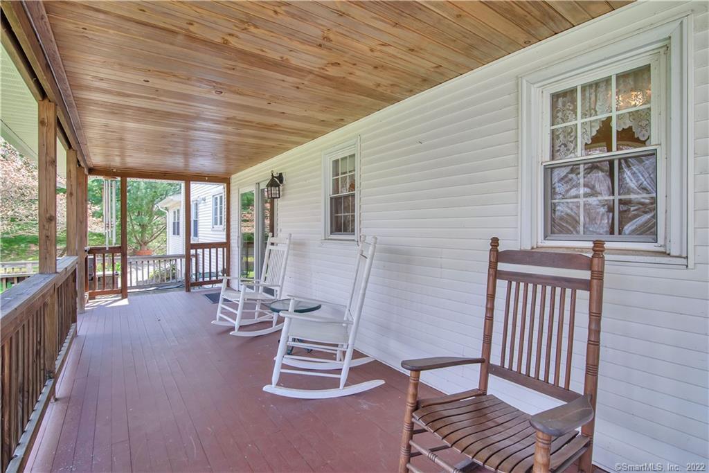 Covered front porch with a wood ceiling, white siding, and rocking chairs.