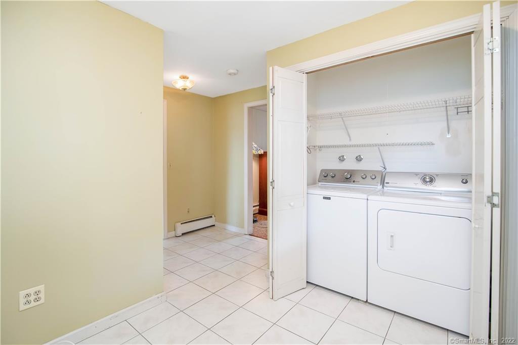 Laundry area with washer and dryer in an open closet and a tiled floor.