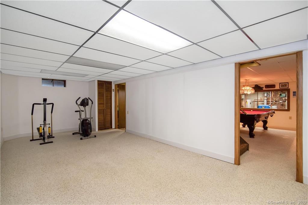 Basement recreation room with exercise machines and a pool table visible through the doorway.