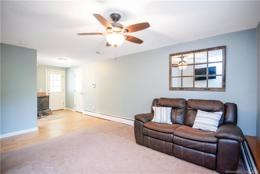 Living room with a brown leather sectional, ceiling fan, and adjoining tiled entry area.