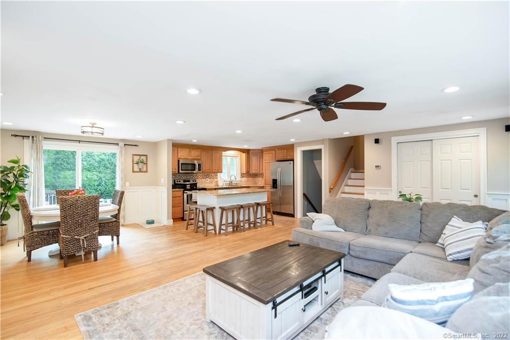 Open-plan living room and kitchen with a gray sectional, island seating, and sliding doors overlooking greenery.