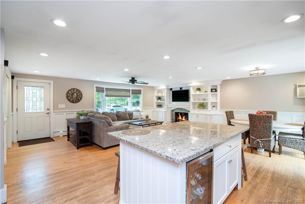 Open-plan kitchen and living room with a granite island, fireplace, and built-in shelving.