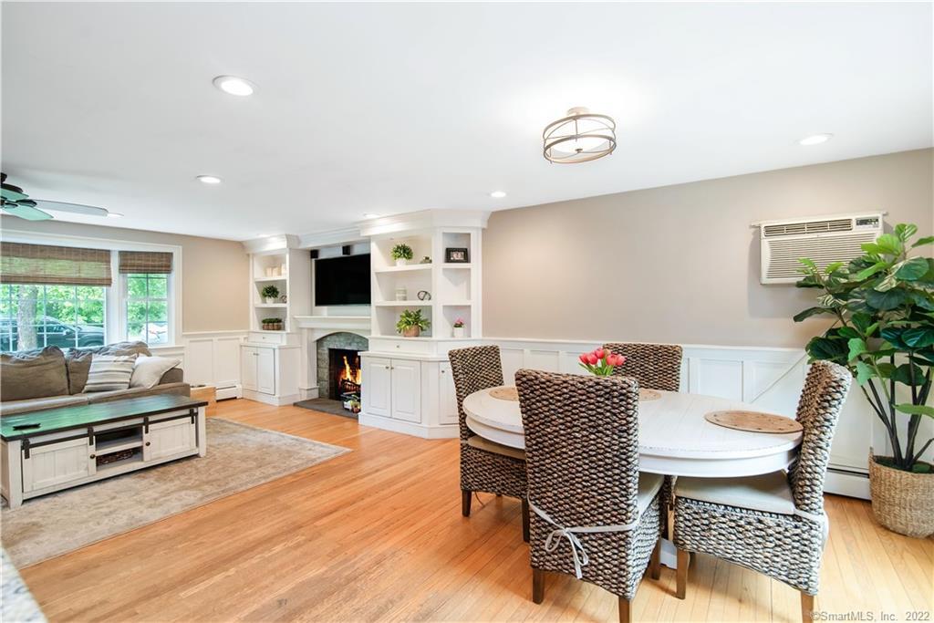 Open-plan living and dining room with built-in shelving, a fireplace, and a round table.