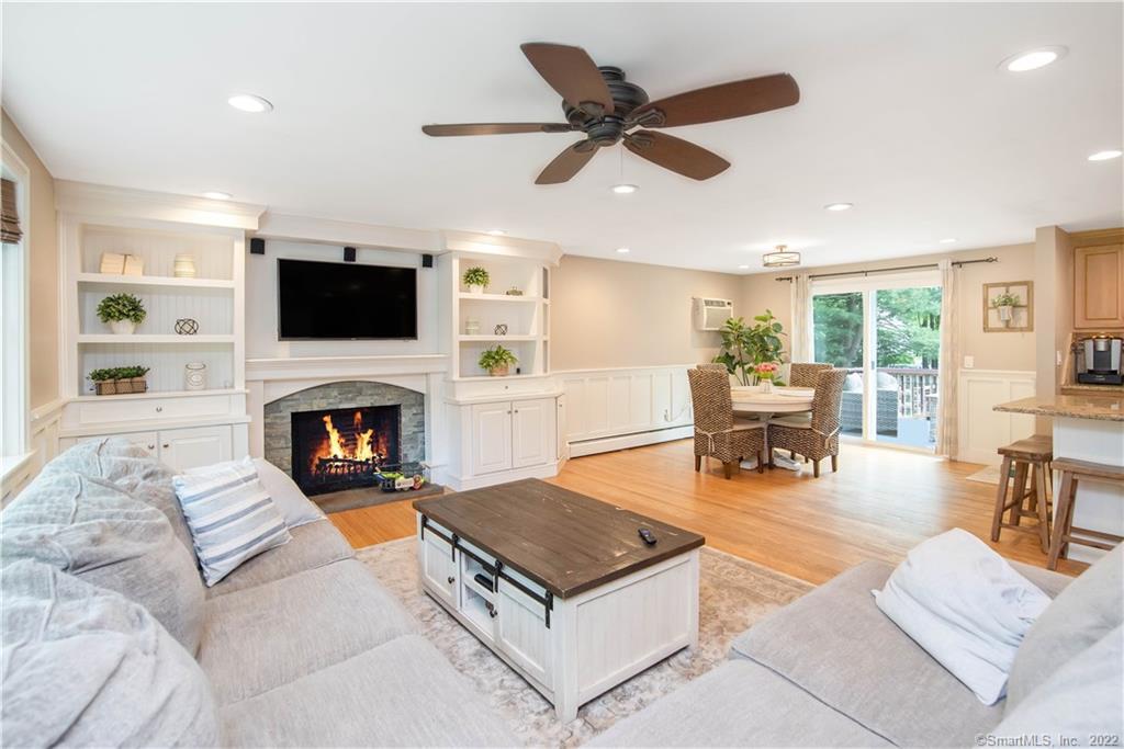 Living room with a stone fireplace, white built-ins, sectional sofas, and sliding doors to a deck.