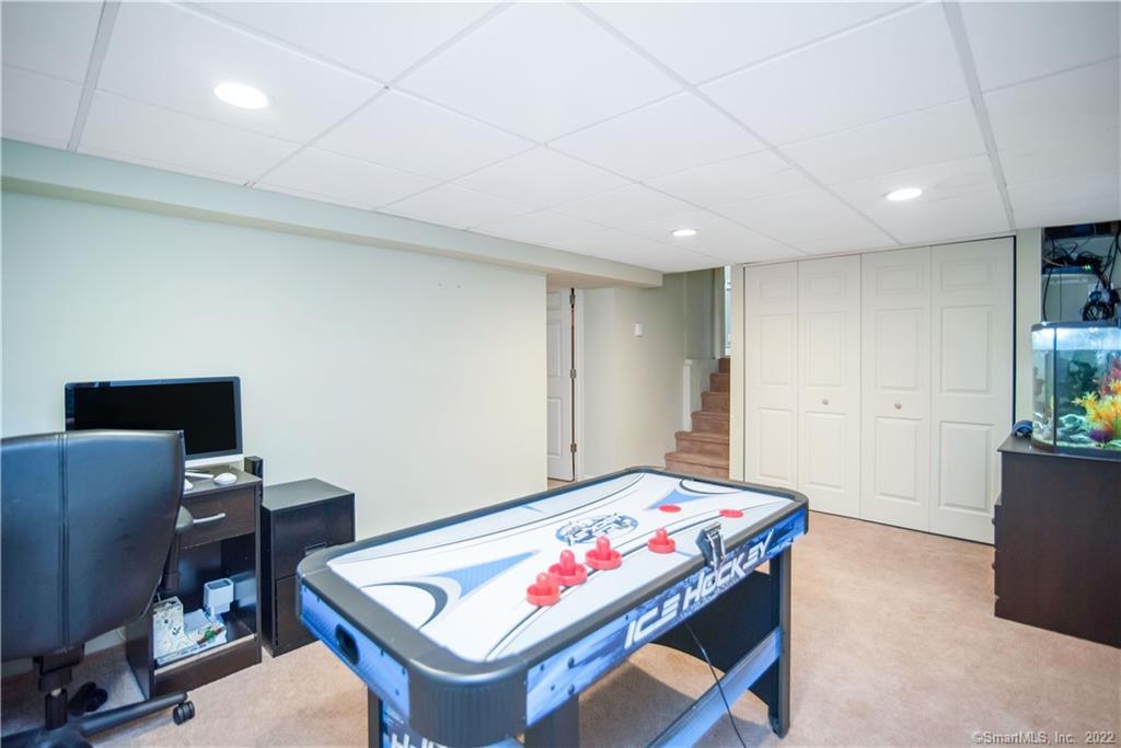 Basement game room with a blue air hockey table, desk, aquarium, and stairs.