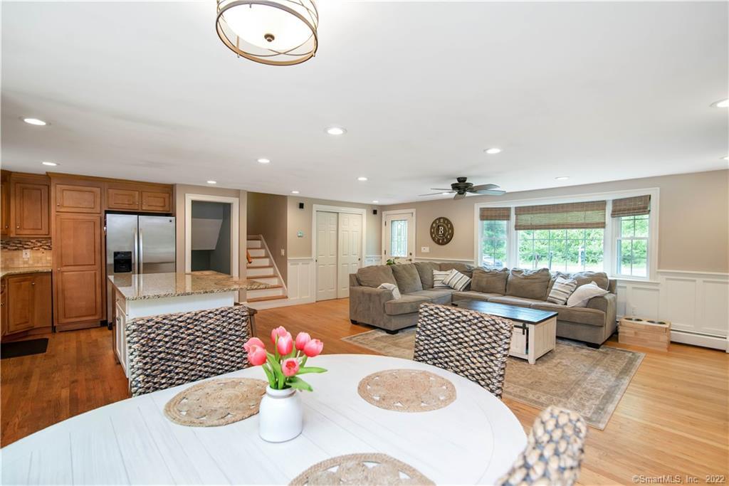 Open-plan living room and kitchen with a gray sectional, wood cabinetry, and large windows.