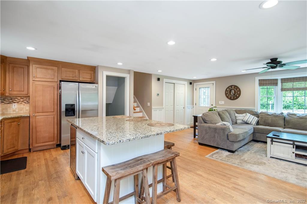 Open-plan kitchen and living room with a granite island, wood cabinetry, and gray sectional.