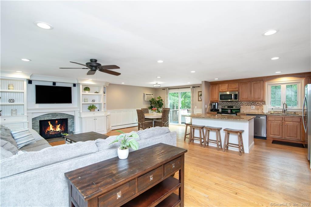 Open living room and kitchen with a fireplace, white sectional, wood cabinetry, and breakfast island.