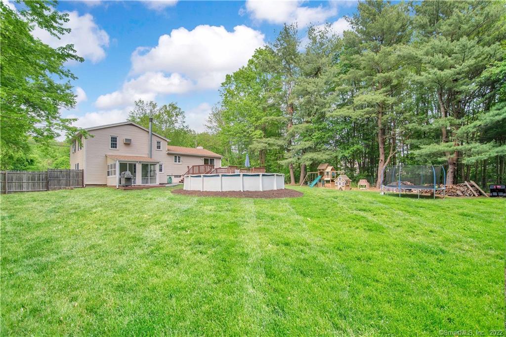 Two-story home and spacious backyard with an above-ground pool, playset, and surrounding trees.