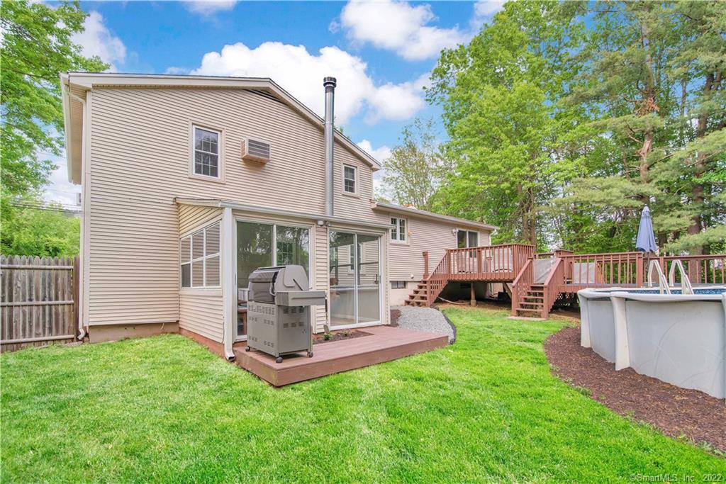 Beige two-story home with a glass sunroom, raised deck, and above-ground pool in the backyard.