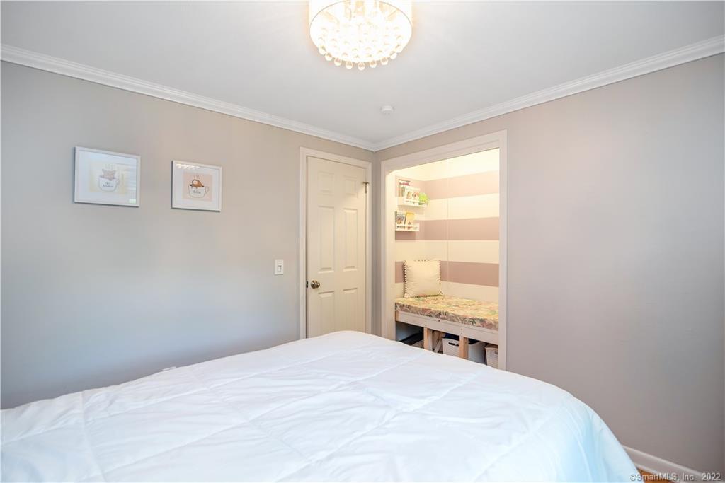 Bedroom with a large white bed and an adjoining striped-wall sleeping nook.