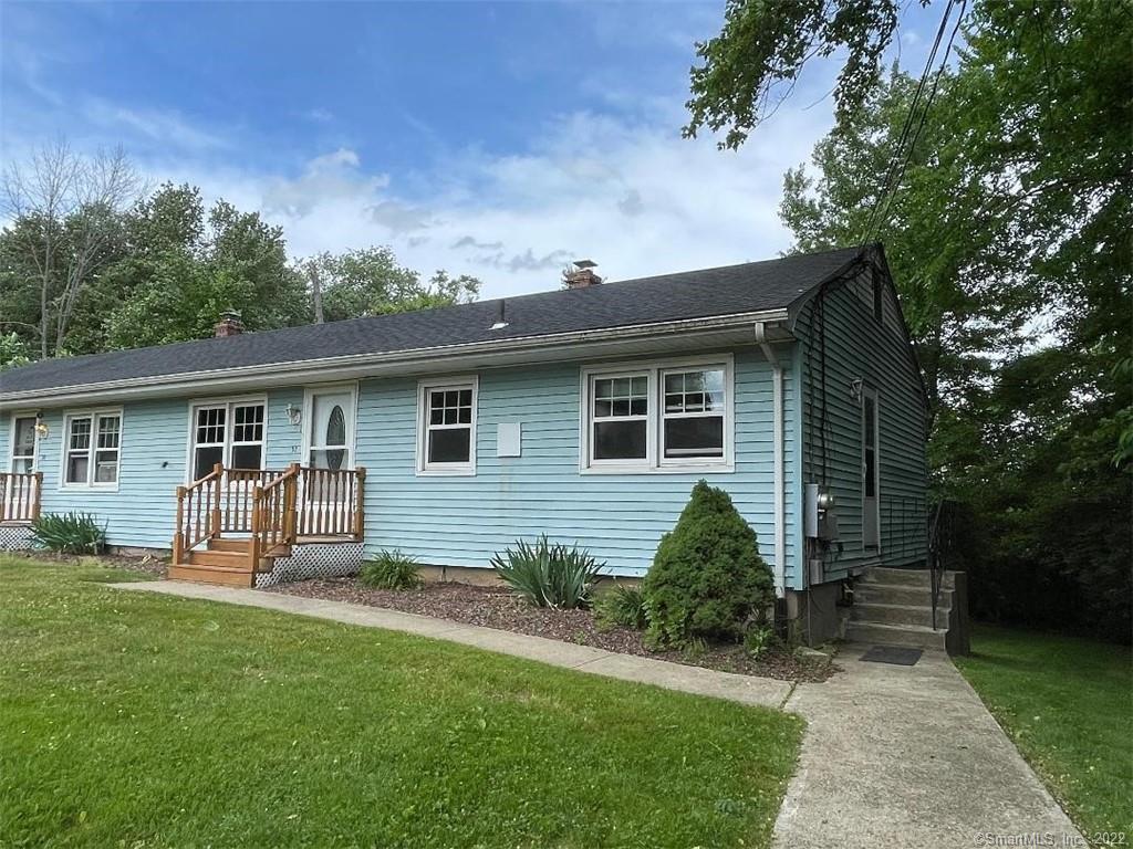 Light blue single-story home with a wooden entry porch and curved walkway across the front lawn.