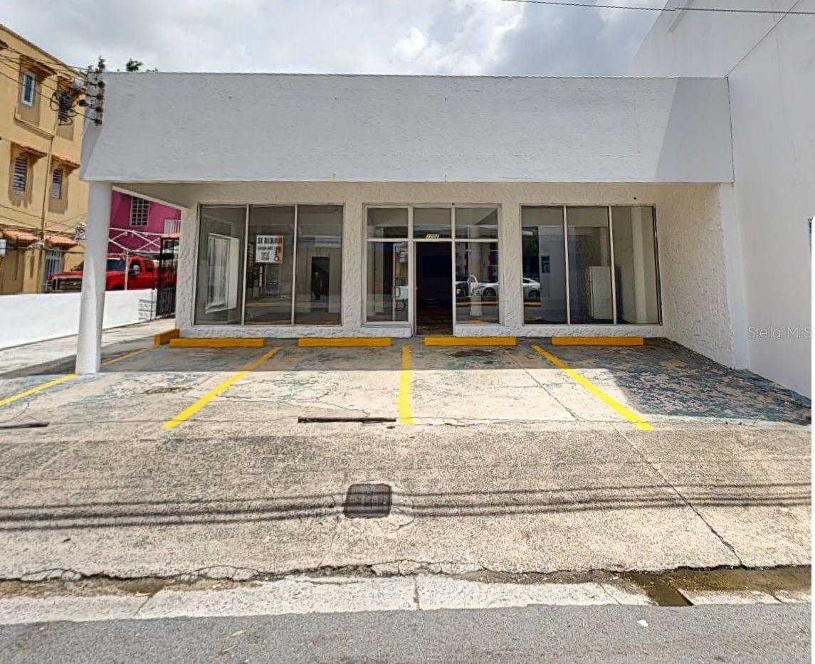 Commercial storefront with broad glass frontage and yellow-marked parking spaces.