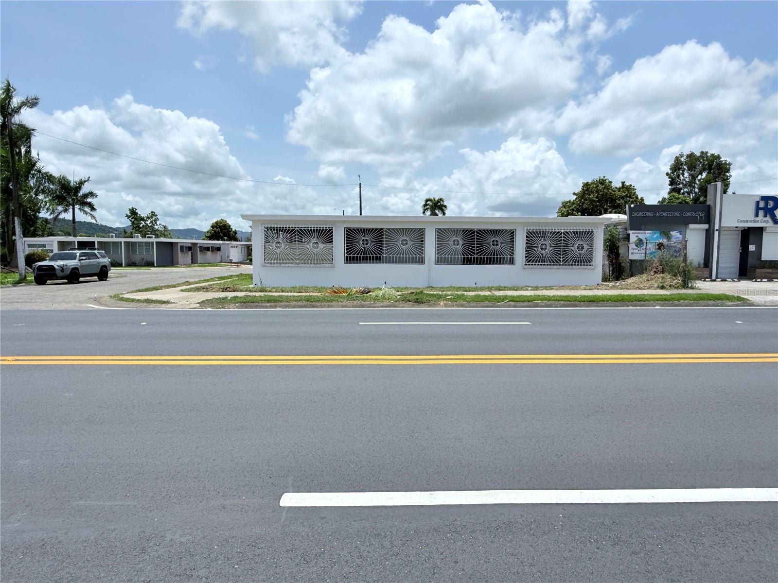 Low white roadside building with decorative metal window grilles across the facade.