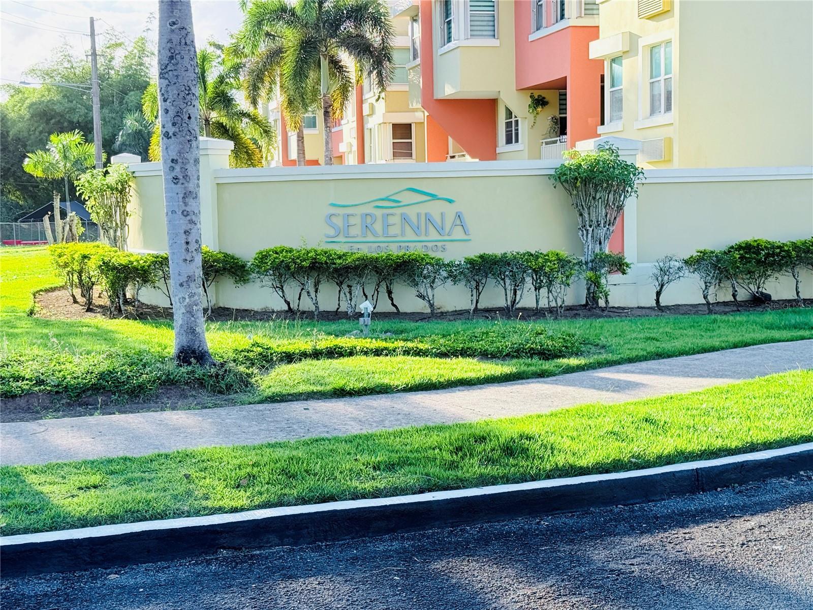 Serenna en Los Prados entrance sign in front of colorful apartments and palm trees.