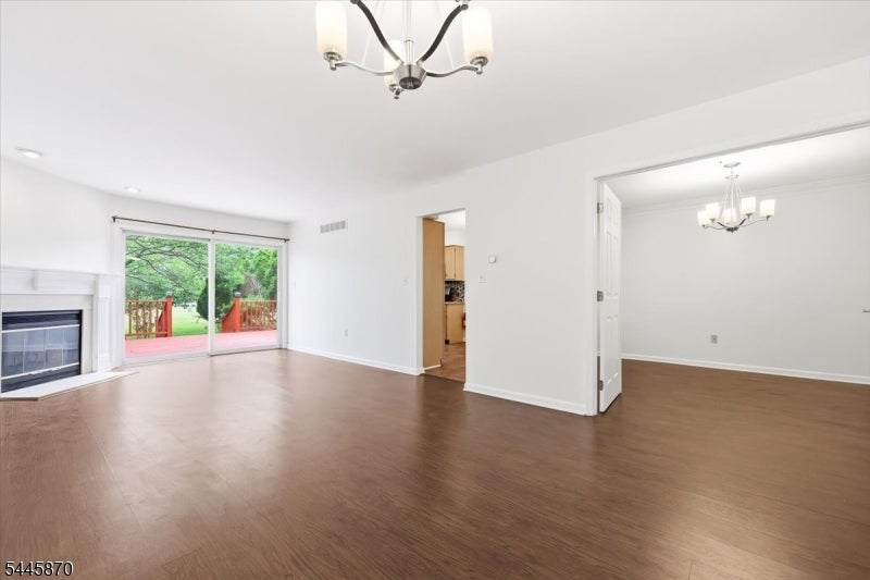 Vacant living and dining area with wood flooring, a fireplace, and sliding doors to a deck.