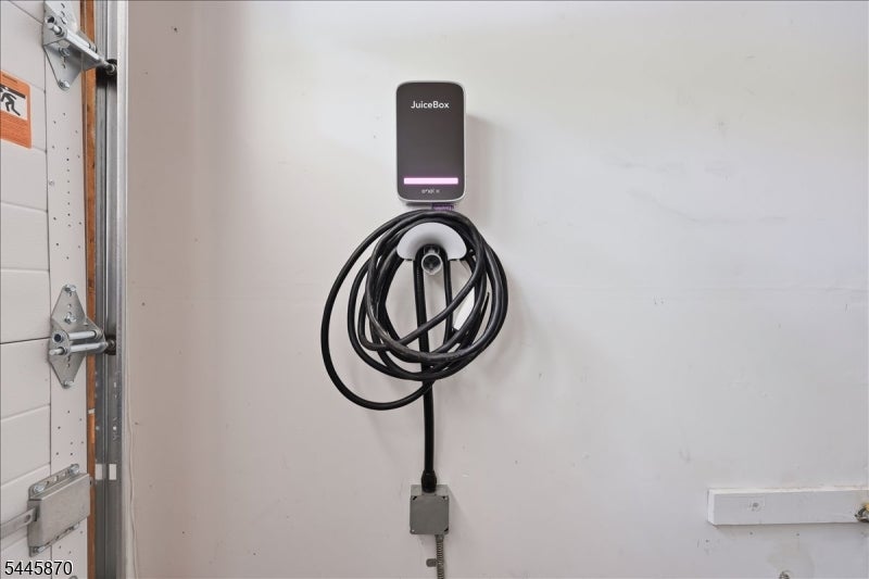 Garage wall with a JuiceBox EV charger and its coiled cable beside the garage door.