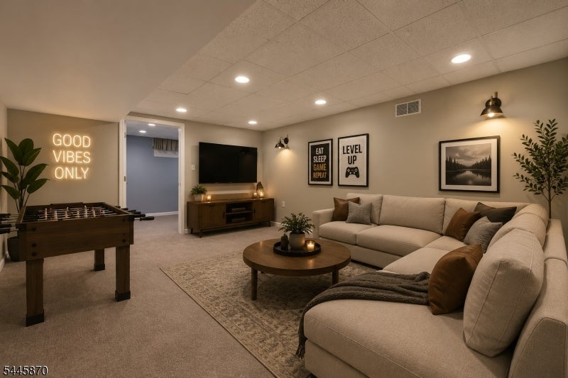 Furnished recreation room with a sectional sofa, foosball table, and gaming-themed wall art.