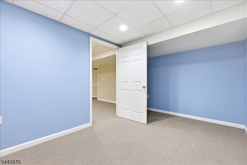 Empty blue room with beige carpet and an open white door.