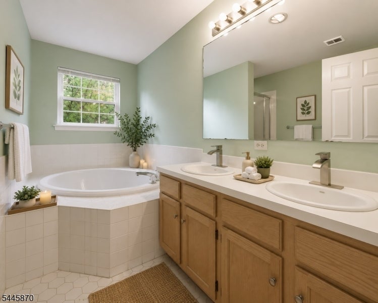 Bathroom with a corner jetted tub and double-sink wood vanity.
