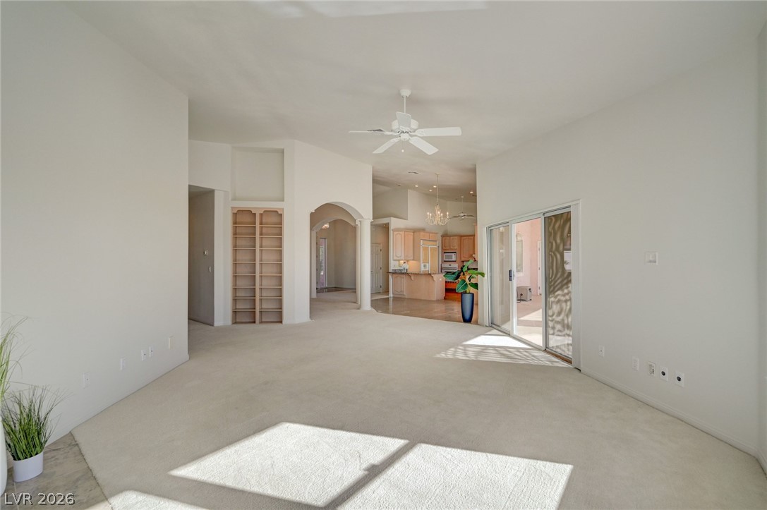 Spacious living room with light carpet, ceiling fan, and sliding glass doors to a patio.