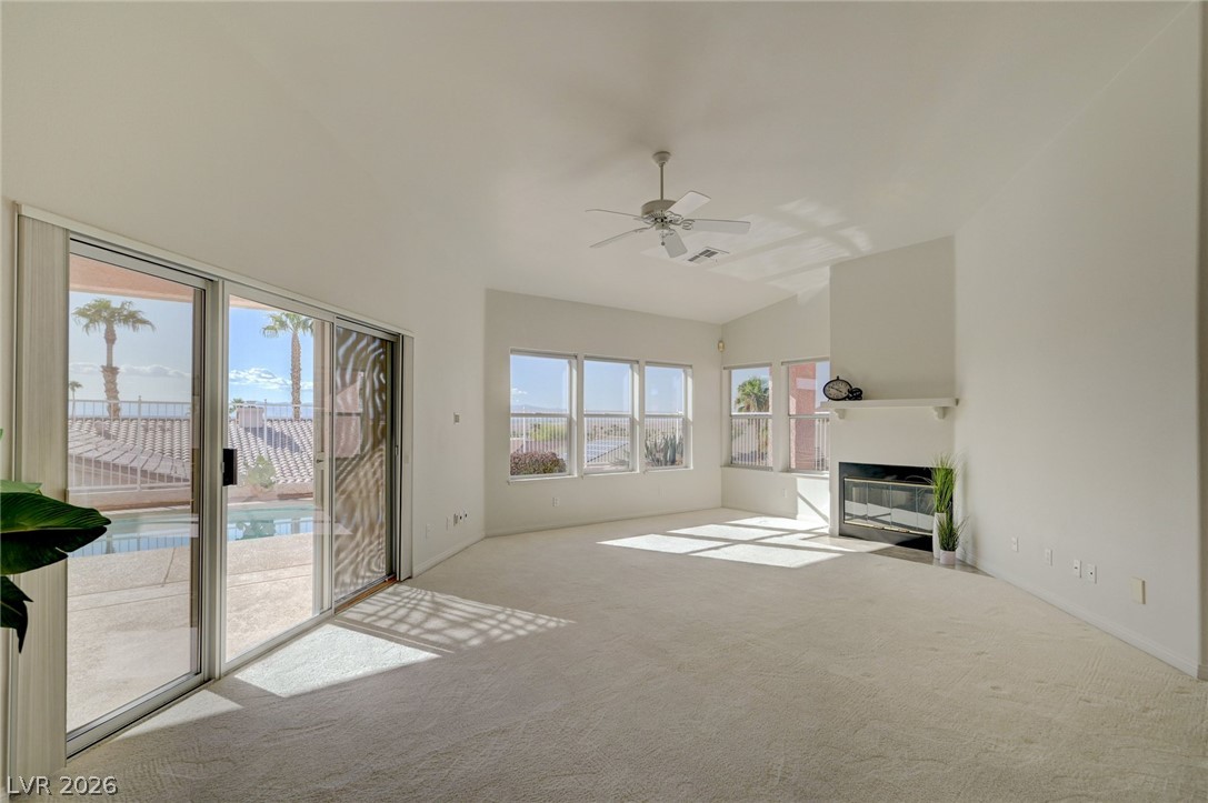 Vacant living room with a fireplace and sliding glass doors overlooking the pool patio.